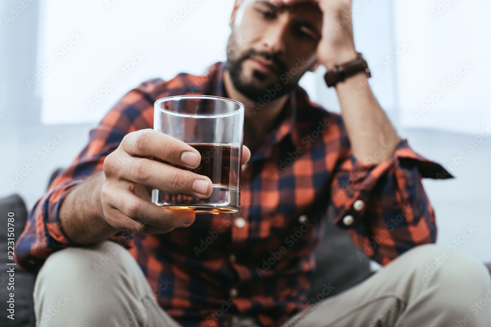 close-up shot of depressed young man with glass of whiskey
